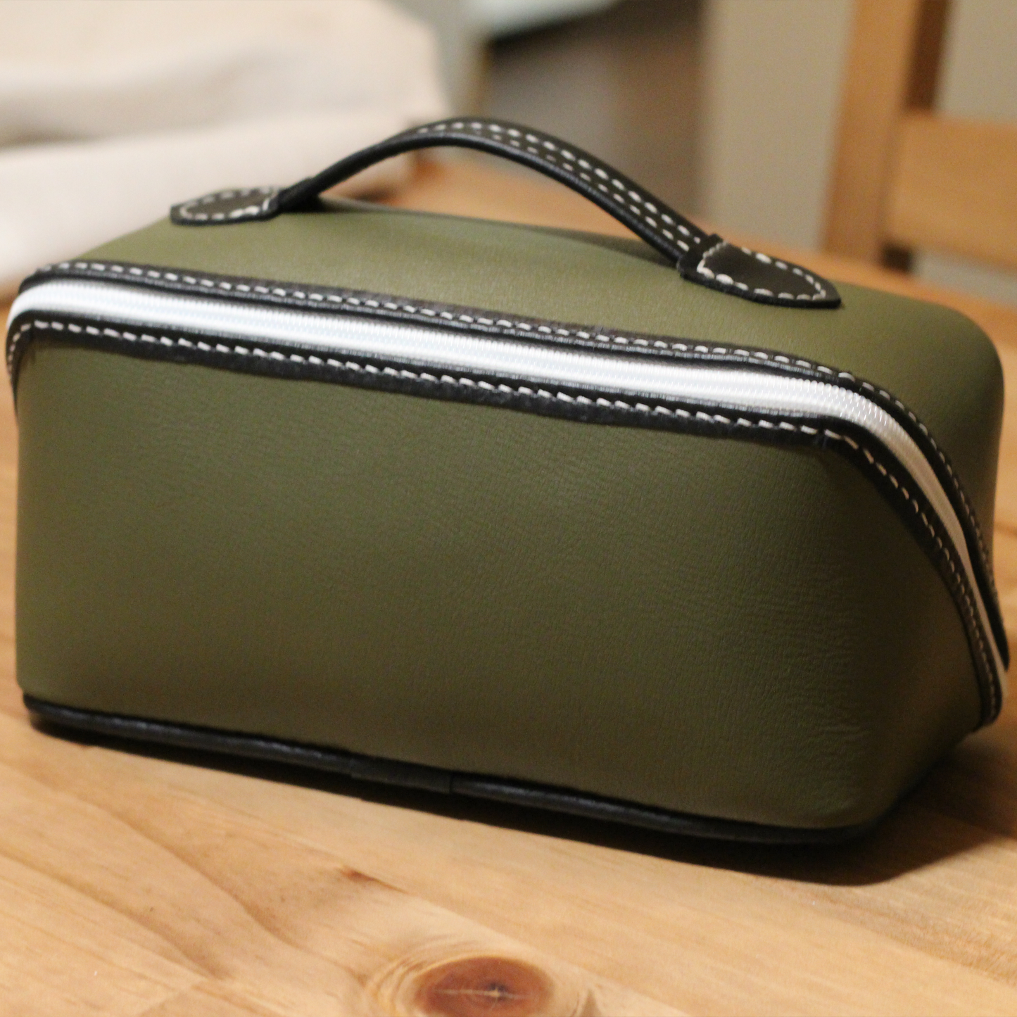 Handmade leather dopp kit made using a DIY pattern surrounded by leathercraft tools on a wooden table