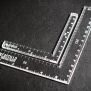 Two clear plastic right angle rulers with measurement markings on a dark surface with 'Castillo Heritage Crafts' branding