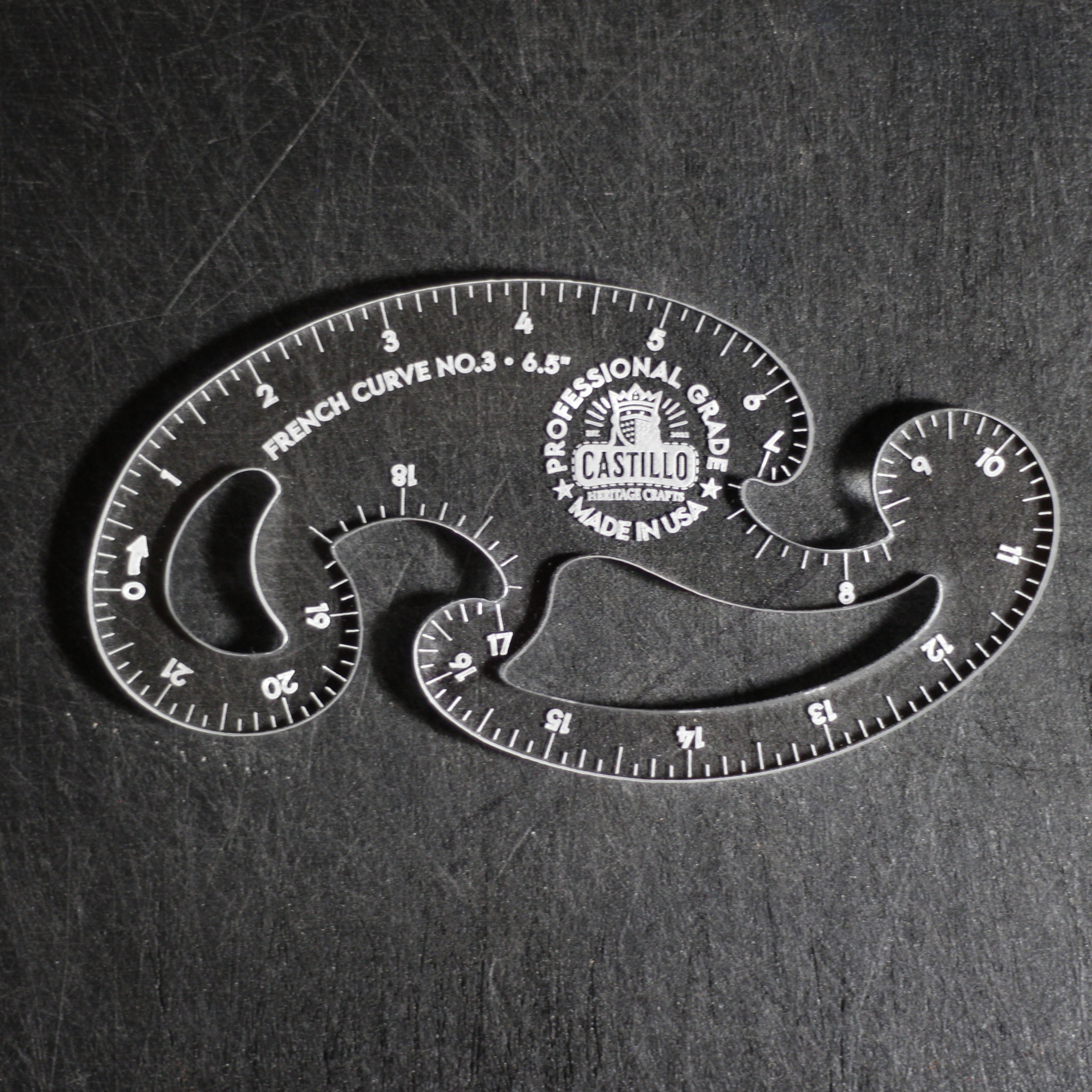 A clear plastic French Curve No. 3 measuring tool by Castello, shown on a dark textured background.