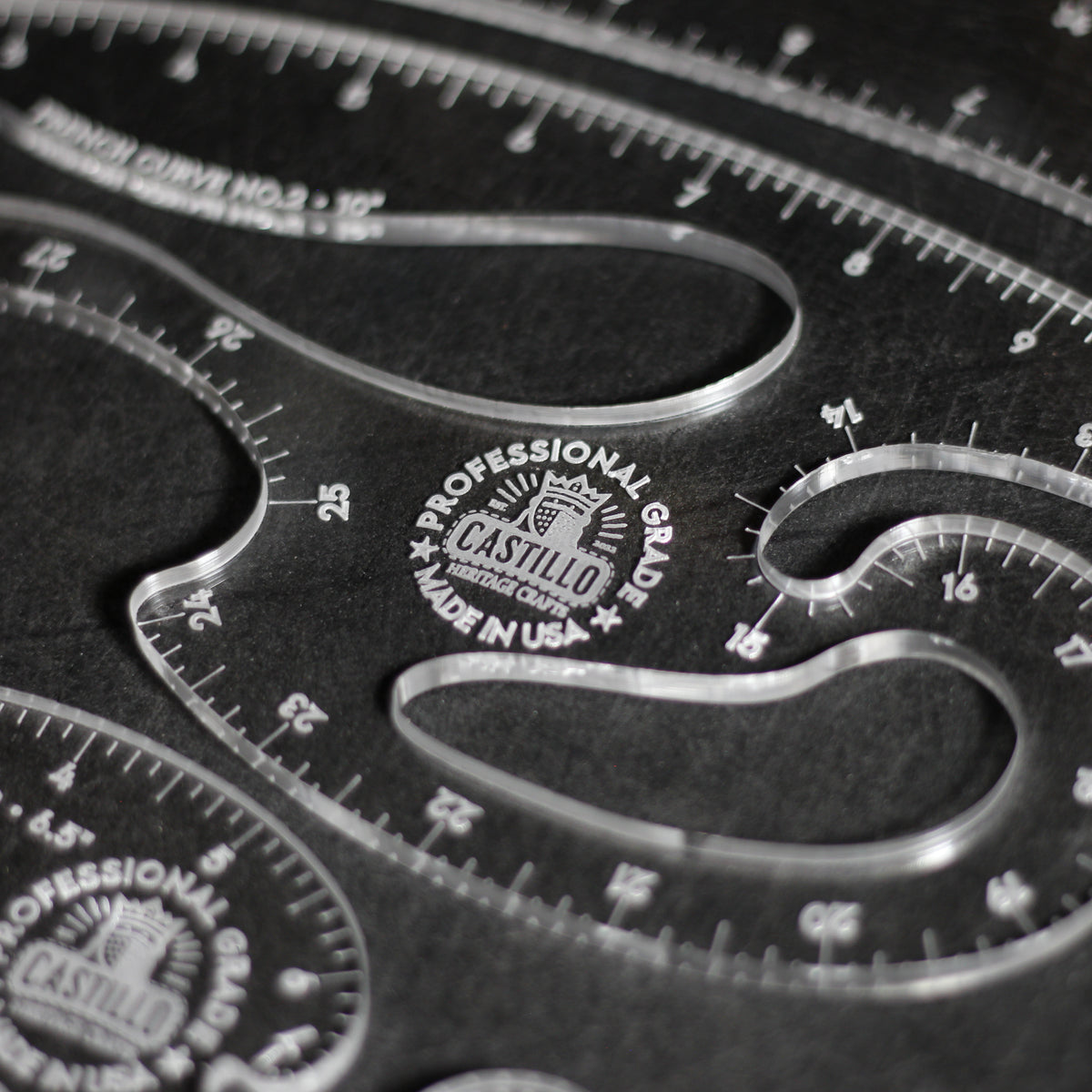 Close-up of a clear acrylic drafting ruler set with curved measurement guides and engraved Castilio branding on a dark background.